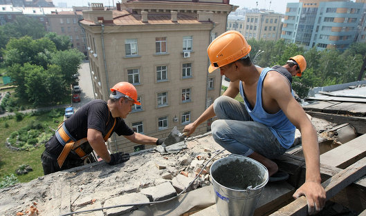 *Рабочие ремонтируют фасад и крышу жилого дома
