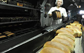 Работница вынимает из формы готовый хлеб