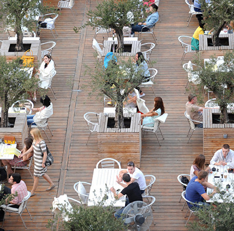Посетители за столиками в летнем кафе