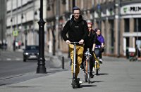 Жители Москвы едут по улице на велосипедах и самокатах