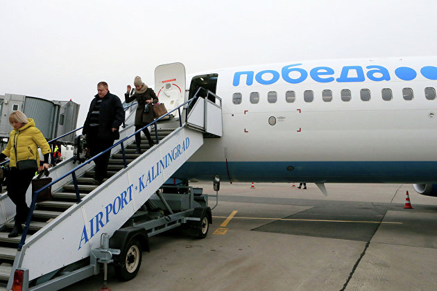 Пассажиры сходят с самолета российской низкобюджетной авиакомпании "Победа", осуществившего первый рейс по маршруту Москва-Калининград