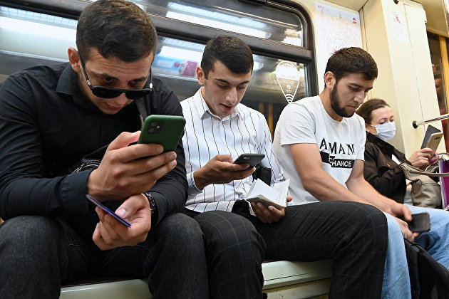 Мужчины со смартфонами в вагоне московского метро