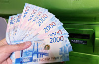 Клиент Сбербанка вносит наличные деньги в банкомат