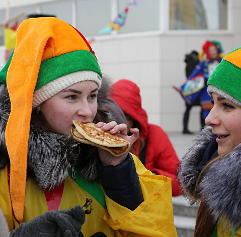 Участники кушают блины во время массового масленичного гуляния "Блинно-сырное веселье" в Белгороде