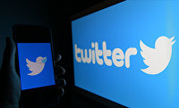 Логотип социальной сети Twitter на экранах мобильного телефона и компьютера