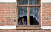 Женщина смотрит из окна своего дома в городе Чекалин Тульской области