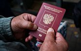 Мужчина держит в руках свой паспорт в день выборов депутатов Государственной Думы РФ