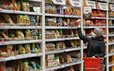 Покупательница выбирает макаронные изделия в гипермаркете "Ашан"