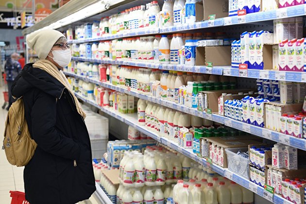 Покупательница выбирает товар в молочном отделе гипермаркета