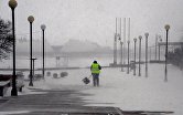 Работник коммунальной службы на набережной Спортивной гавани во время снежного циклона во Владивостоке