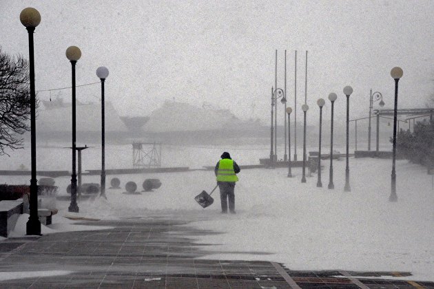 Работник коммунальной службы на набережной Спортивной гавани во время снежного циклона во Владивостоке