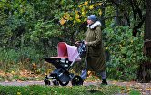 Женщина с детской коляской гуляет в музее-заповеднике "Коломенское" в Москве