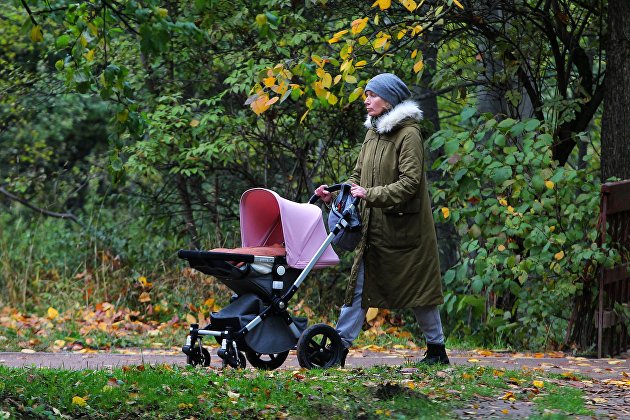 Женщина с детской коляской гуляет в музее-заповеднике "Коломенское" в Москве