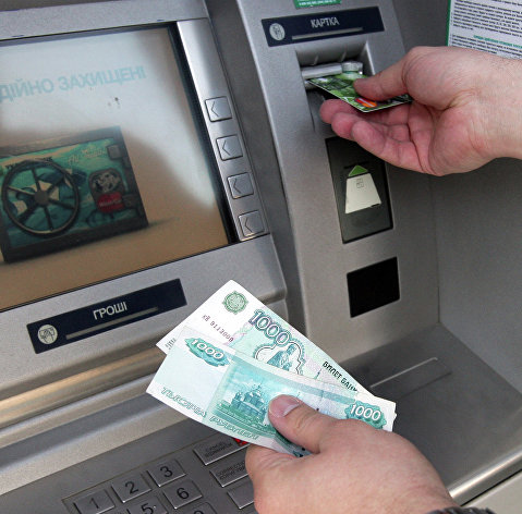 Житель Симферополя снимает наличные деньги через банкомат. Архивное фото