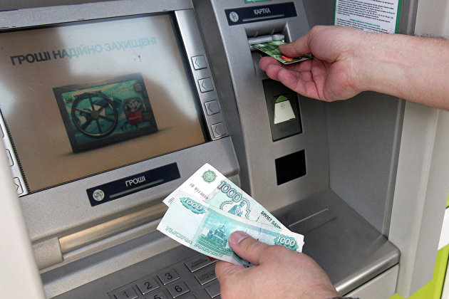 Житель Симферополя снимает наличные деньги через банкомат. Архивное фото