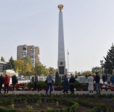 Люди возле стелы "Мелитополь - город воинской славы" на площади Победы в Мелитополе