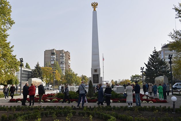 Люди возле стелы "Мелитополь - город воинской славы" на площади Победы в Мелитополе