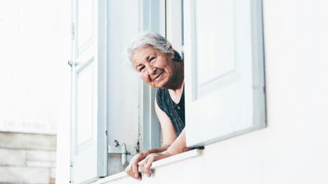 Пожилая женщина выглядывает из окна