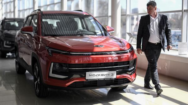 Мужчина осматривает автомобиль Москвич 3 в дилерском центре