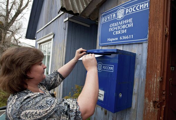 Женщина опускает письмо в почтовый ящик Почты России