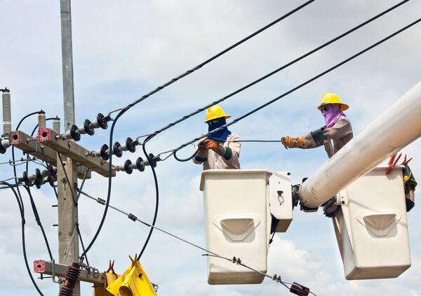 Монтеры крепят провода на новой опоре линии электропередачи