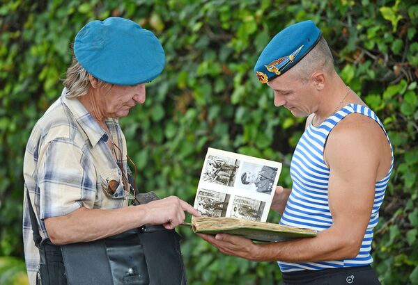 Бывшие десантники разных поколений рассматривают фотографии в альбоме