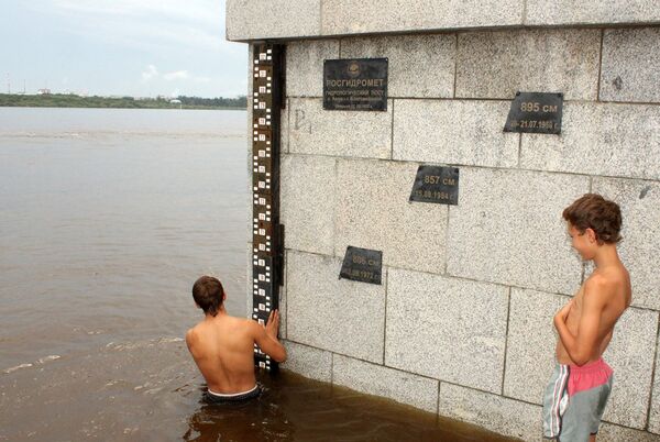 Молодежь на набережной Амура рядом с отметками высоты уровня воды