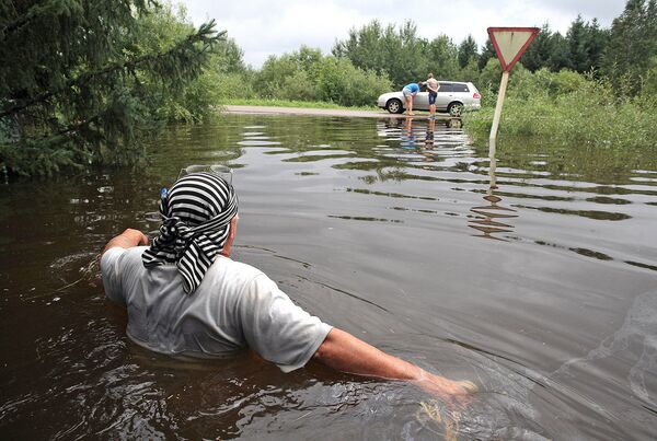 Мужчина идет по подтопленной дороге в поселке Владимировка Благовещенского района