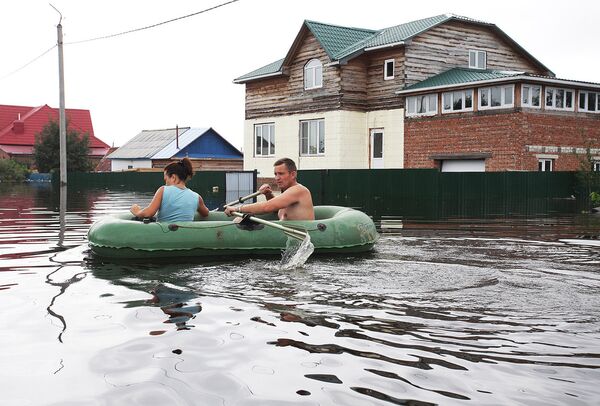 Жители поселка плывут на резиновой лодке по подтопленной улице в поселке Владимировка Благовещенского района