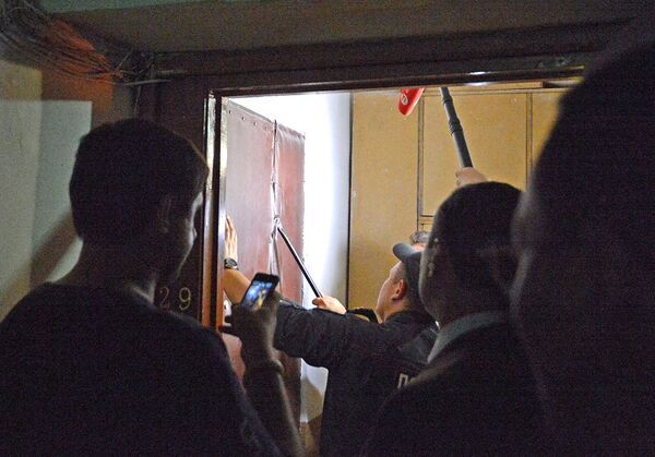 Сотрудники правоохранительных органов вскрывают дверь в квартиру