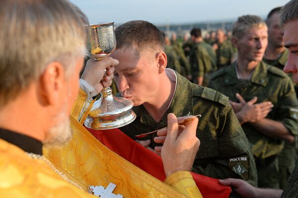 Российские солдаты причащаются во время православной литурги в палаточном городке.