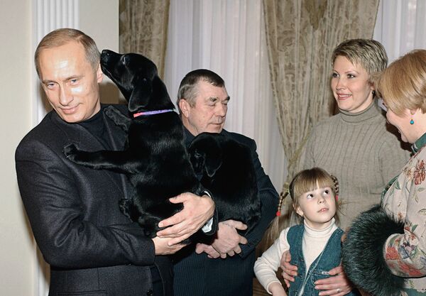 Путин дарит щенков, рожденных его собакой лабрадором Кони, пенсионеру из Ростовской области Алексею Белевцу и шестилетней девочке Кате из Смоленска. 1 марта 2004 года.