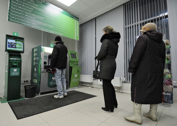 Посетители стоят в очереди к банкомату