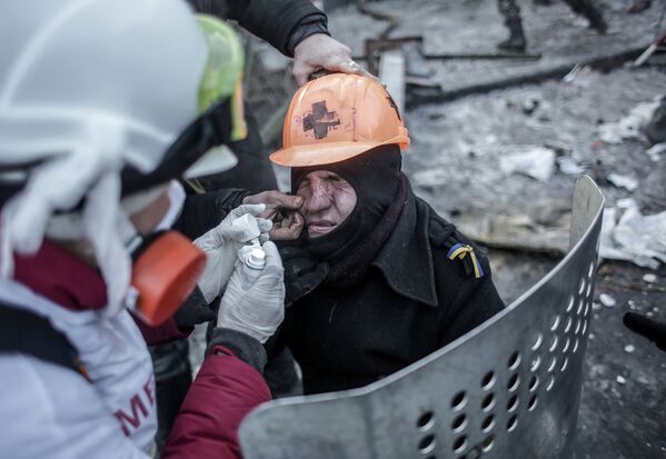 Сторонники оппозиции оказывают медицинскую помощь мужчине, пострадавшему во время столкновений с сотрудниками правоохранительных органов у стадиона Динамо в Киеве.