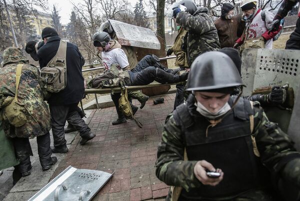 Сторонники оппозиции несут раненного за баррикады на площади Независимости в Киеве.