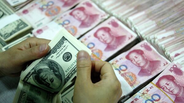 %Банковский служащий пересчитывает доллары рядом с пачками юаней