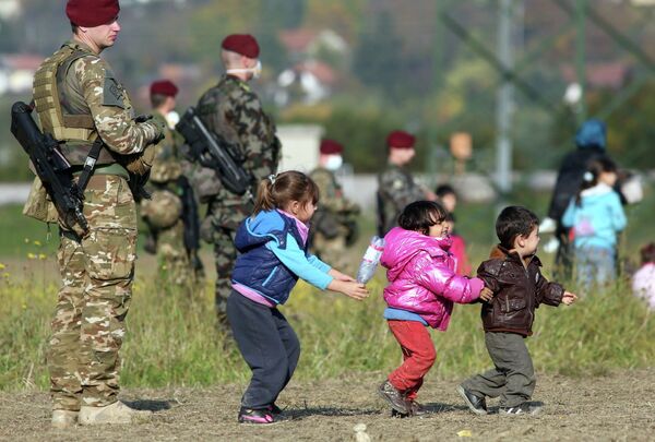 Дети беженцев играют рядом со словенскими военными на хорватско-словенской границе