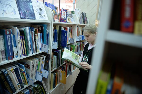 Девочка читает книгу в библиотеке