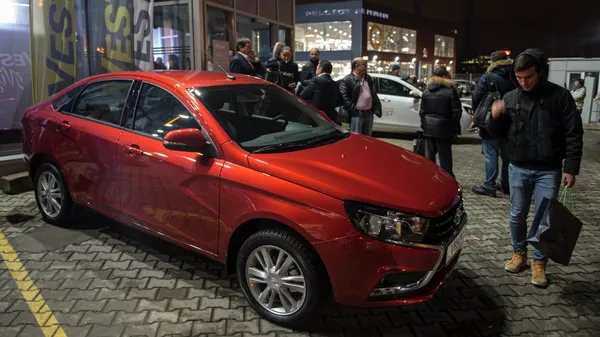 *Молодые люди осматривают автомобиль Lada Vesta после начала продаж в Москве