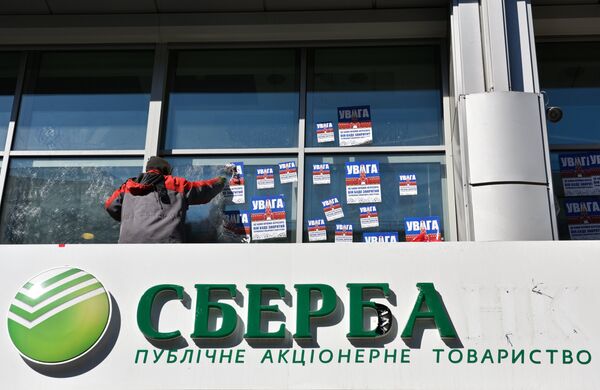 Рабочий очищает фасад центрального отделения дочернего предприятия Сбербанка России в Киеве от листовок