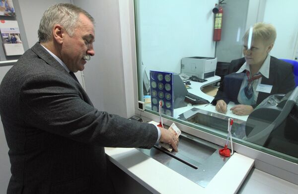 Кассир выдает деньги клиенту операционного зала отделения банка ВТБ-24 на Мясницкой улице