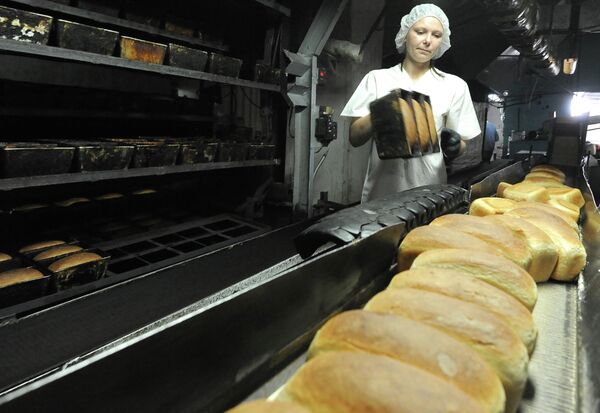 Работница вынимает из формы готовый хлеб