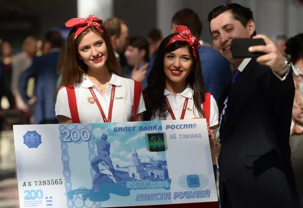 Мужчина фотографируется с образцом банкноты в 200 рублей на международном инвестиционном форуме Сочи 2016