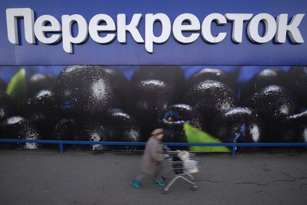 Женщина везет тележку с продуктами у супермаркета торговой сети Перекресток на Славянском бульваре в Москве