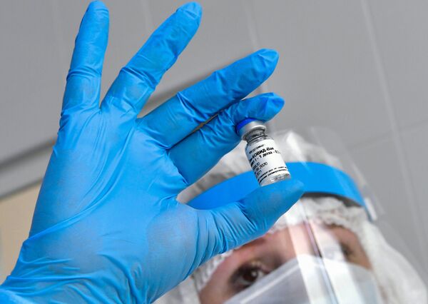  Медсестра держит в руках ампулу с вакциной