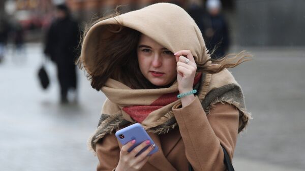 Девушка со смартфоном, ветер