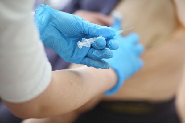 Медсестра делает пациенту прививку от коронавируса