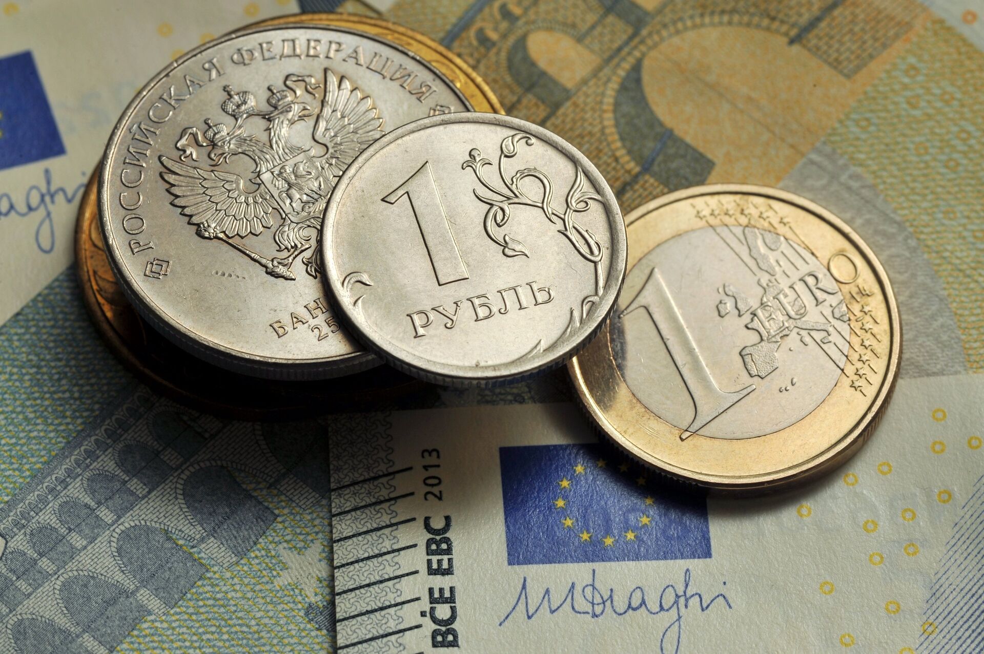 Монеты номиналом 1 рубль и 1 евро на фоне банкноты номиналом 5 евро - ПРАЙМ, 1920, 09.02.2021