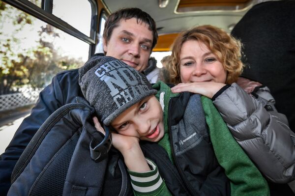 Участники благотворительной программы Поезд надежды с усыновленным мальчиком в салоне автобуса перед отъездом в аэропорт Иркутска.