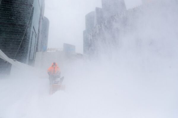 Сотрудник коммунальной службы убирает снег с площади у делового центра Москва-сити